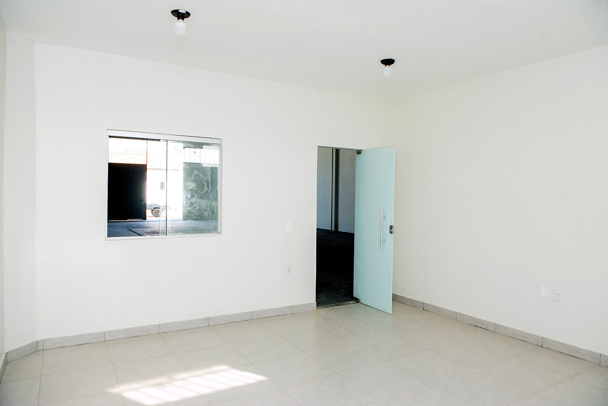 Sala do térreo com janela para o galpão e porta de vidro